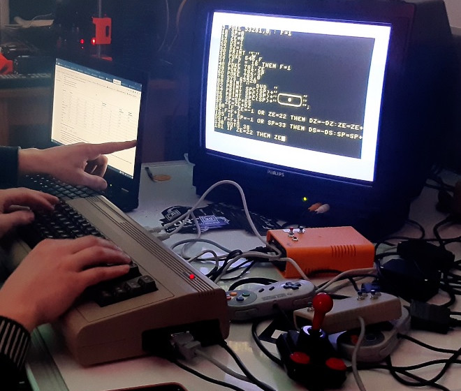 Eine Person zeigt auf einen PC Bildschrim, es sind Code Zeilen zu sehen